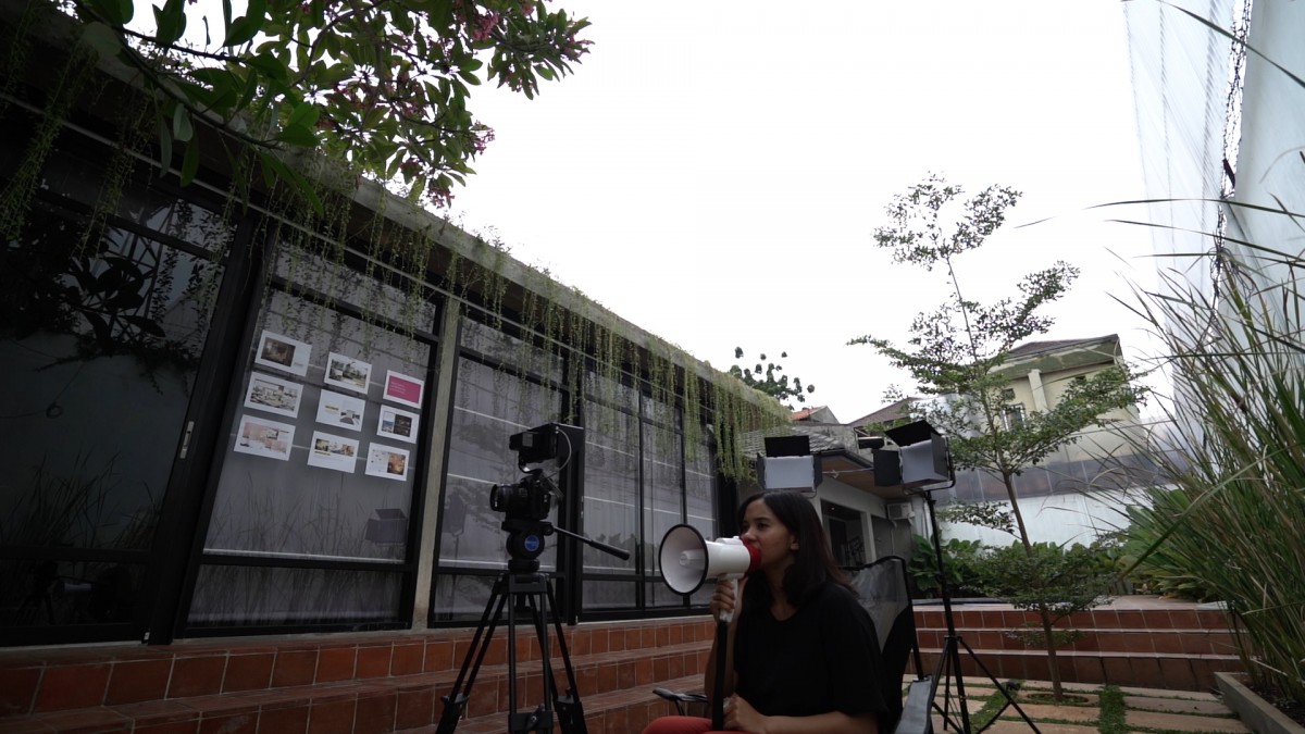 Naya Anindita sedang berbicara menggunakan pengeras suara